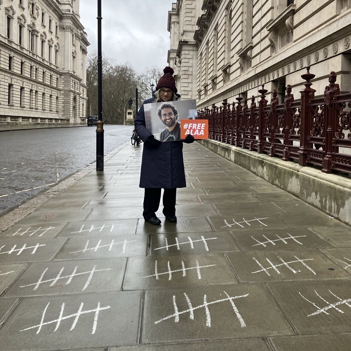 Mona Seif (@monasosh) on Twitter photo Mama held Alaa's photo as she stood this morning outside the FCDO. 
On the ground, chalk marks counting the days Alaa remains in prison beyond his sentence, which also reflects the number of days our mother deprived herself of any nourishment in protest .. DAY 75!! Mama held Alaa's photo as she stood this morning outside the FCDO. 
On the ground, chalk marks counting the days Alaa remains in prison beyond his sentence, which also reflects the number of days our mother deprived herself of any nourishment in protest .. DAY 75!!