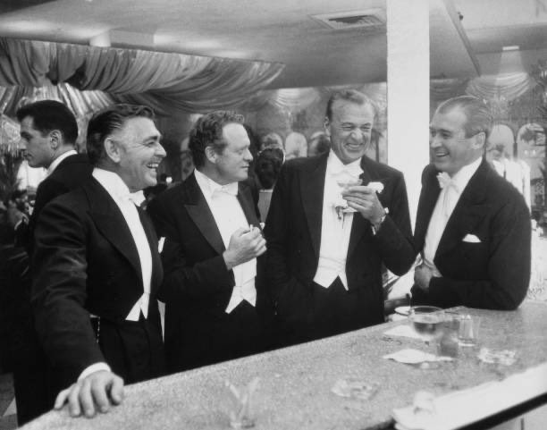 Clark Gable, Van Heflin, Gary Cooper and James Stewart enjoy a joke at a New Year's party held at Romanoff's in Beverly Hills, 1957