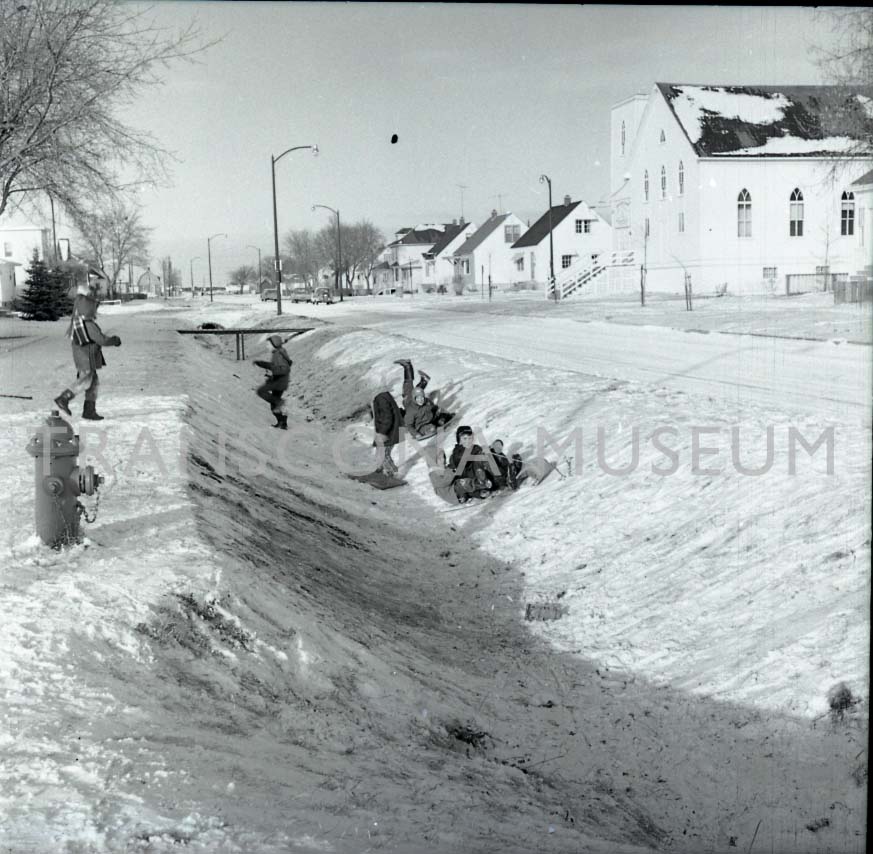 A fan favourite photo: A group of children playing in the snow along a drainage ditch near Madeline Street and Havard Avenue West, ca. 1963. #TMArchives