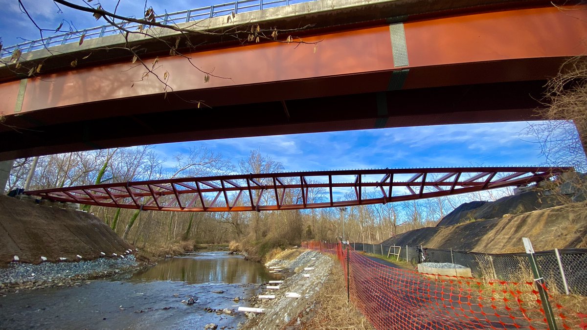 TimSloanDC's tweet photo. WE GOT A TRAIL BRIDGE! The sculptural inverted bowed truss Capital Crescent Trail bridge now spans Rock Creek in North Chevy Chase next to the @PurpleLineMD tracks. #bikeDC #PurpleLineMD #purplelineprogress #CCTrail #LightRail #RockCreek #TrainBridge @purplelinenow @WABADC https://t.co/4iN01njE7O