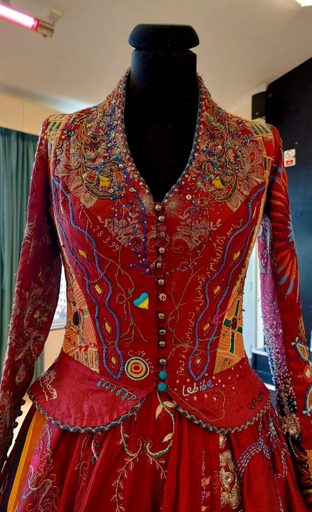 womensart1's tweet photo. The Red Dress Project conceived by artist Kirstie Macleod. Between 2009-2023, 380 embroiderers from 51 countries, many of whom were vulnerable, told their personal stories through embroidery on burgundy silk dupion #WomensArt https://t.co/tzeFm29Uh4