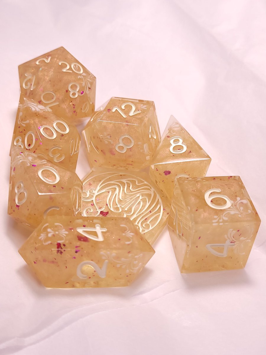 FlutesCreations's tweet photo. Golden Rose Glow is a golden resin with a pink interference powder and pink foil flake. Cream flourishes and a cream inking finish off this set. 

#flutescreations #dice #handmadedice #ttrpg https://t.co/LiNplPPxF8