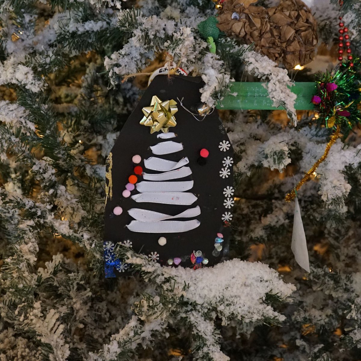 “Jingle bells tactile Christmas tree.” by Eitan, age 8. This is such a wonderful way to create a tactile tree!
Eitan laced white ribbon through black paper to create the shape of a tree and topped it with a golden gift bow. Well done! #TreeForTreats