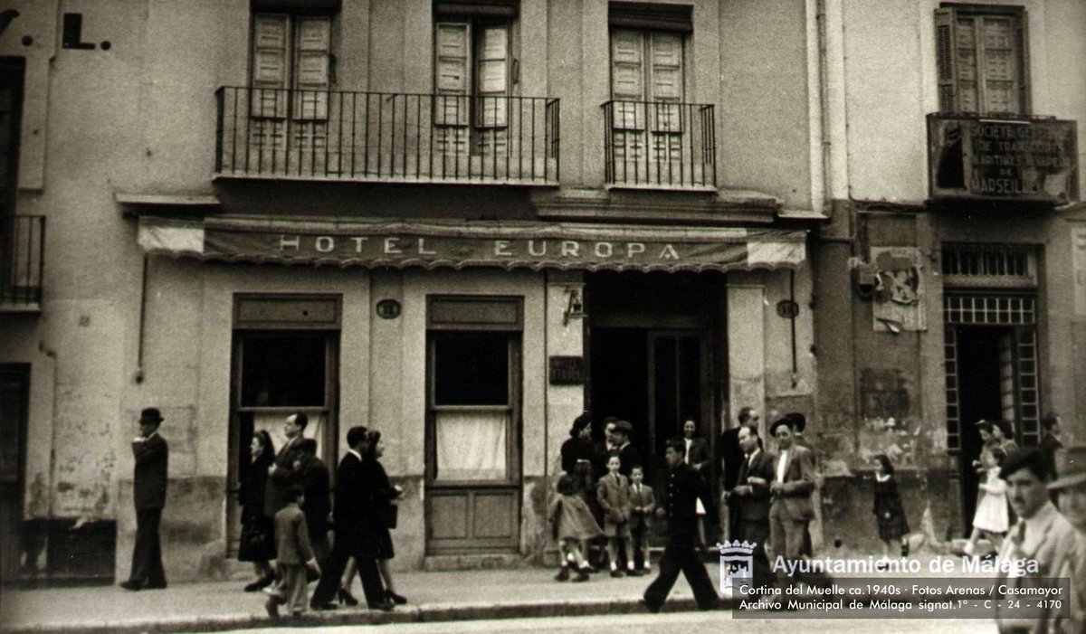 1/2 Paseando por la Cortina del Muelle en los primeros años 1940s. En las fachadas se reconocen los rótulos de la Compañía de Transportes Generales, el Hotel Europa, el Bar Avenida y la que parece ser Société générale des transports maritimes (...) de Marseille...