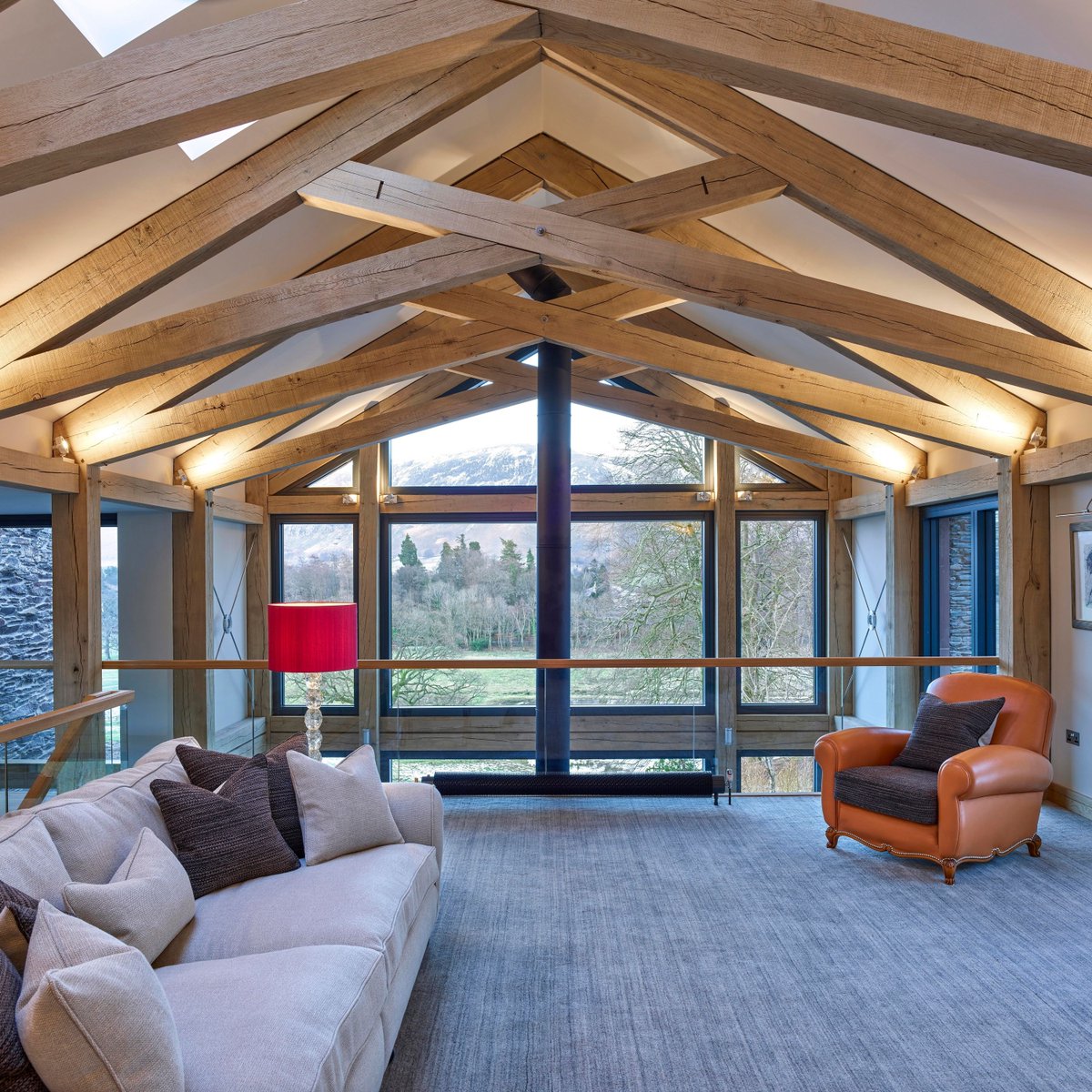 A spacious extension to a Cumbrian farmhouse blends traditional framing elements with a sleek contemporary aesthetic. The open barn-style layout harmonises with the surrounding landscape, while expansive glazed panels frame sweeping views of the Cumbrian countryside.