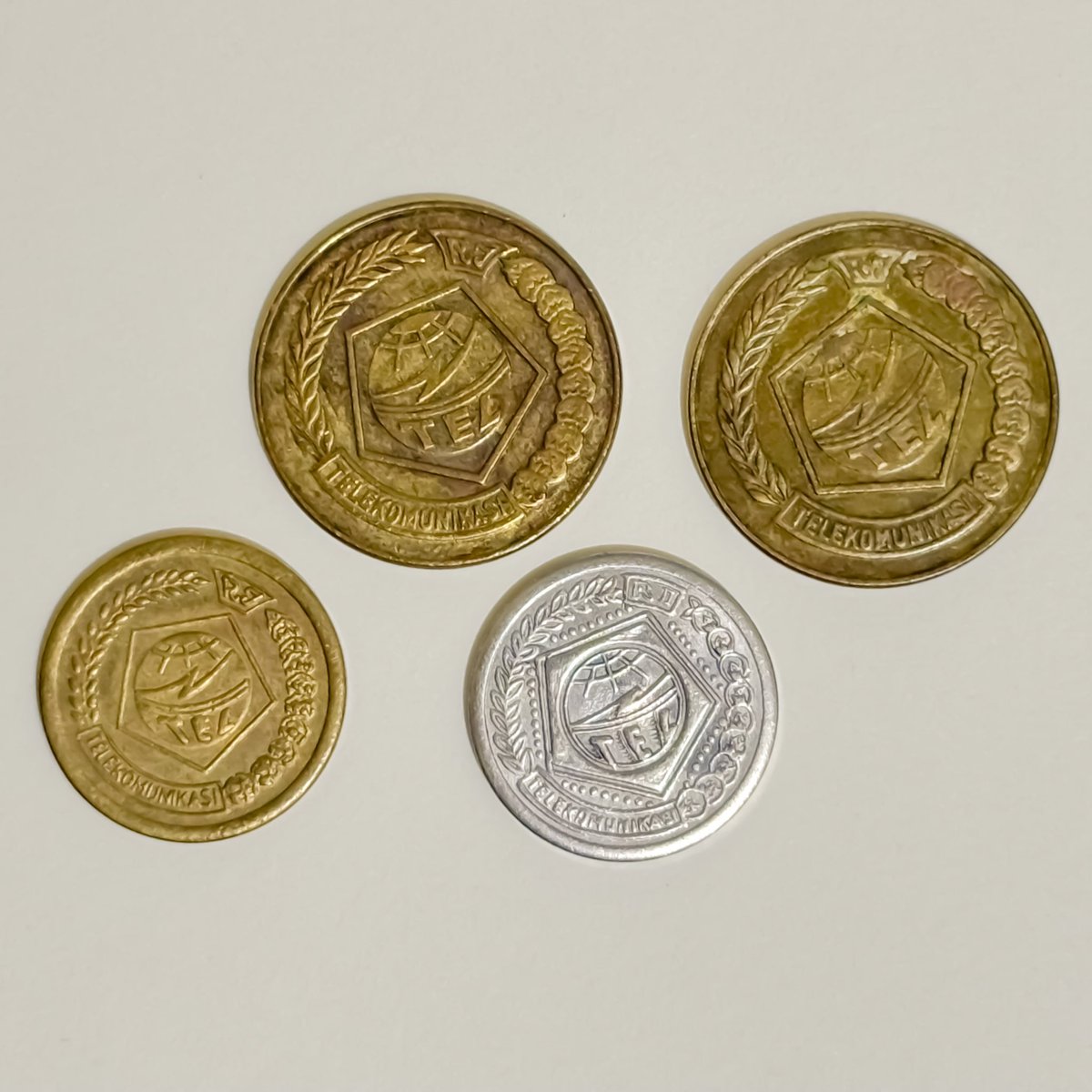 Artefak sejarah berupa token telefon dari era Perumtel yang digunakan untuk mengoperasikan telefon umum di Indonesia, menggantikan uang tunai. Koin berlambangkan logo PN Telekomunikasi, pendahulu Perumtel dan Telkom Indonesia.