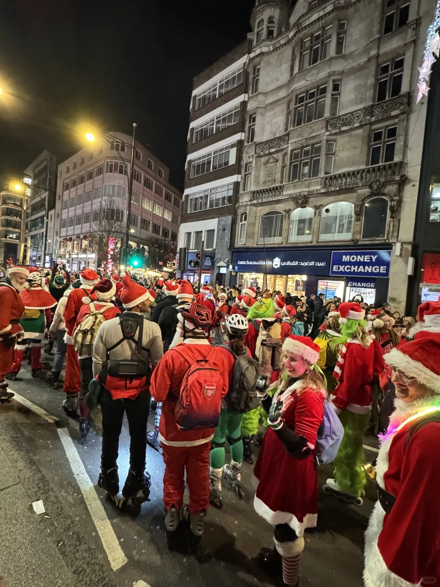 CeCeFrey8's tweet photo. A festive crowd gathering on a city street, with participants wearing Santa costumes https://t.co/WEFAyUzg30
