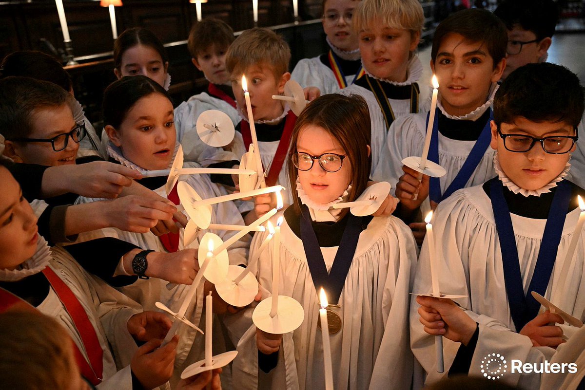 Choristers light candles during a rehearsal for Christmas services at St Paul's Cathedral in London photo by Jaimi Joy for Reuters