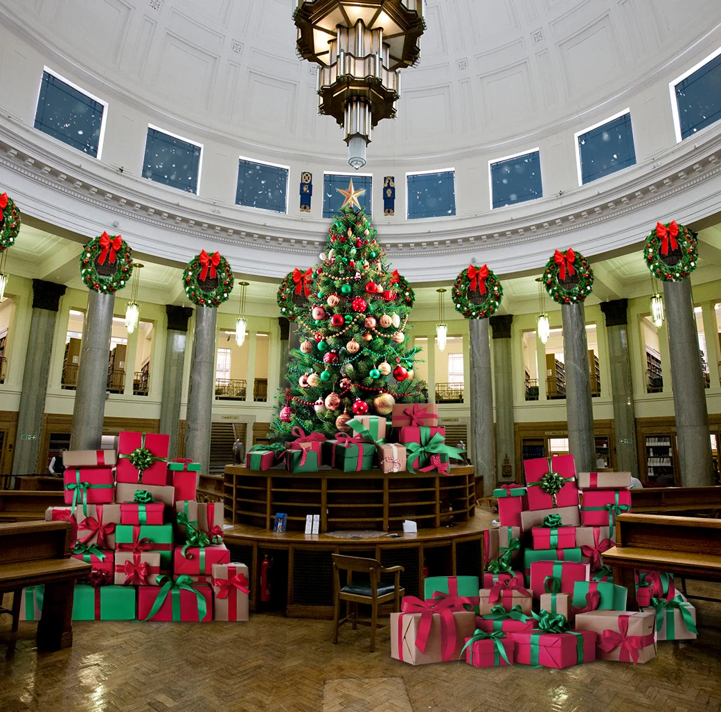 The man area of Brotherton library. A Christmas tree is on top of the central round desks, with piles of presents on either side. The columns are decorated with Christmas wreaths.
