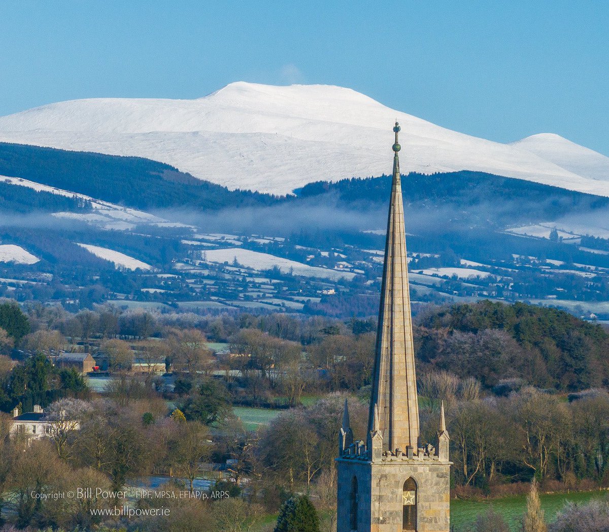 brigobhann's tweet photo. I’ve been planning to take this image for a long time. Finally got around to it. Galtymore on the Galtee Mountains makes a striking backdrop for the Catholic Church steeple in Mitchelstown. #mitchelstown #galtees #Ireland #church https://t.co/WjLsxJWwBV