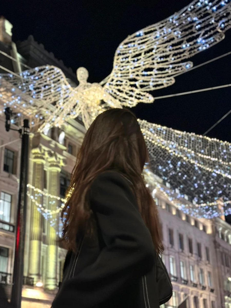 A bustling street adorned with magnificent illuminated angel decorations, capturing the holiday spirit as shoppers fill the surroundings