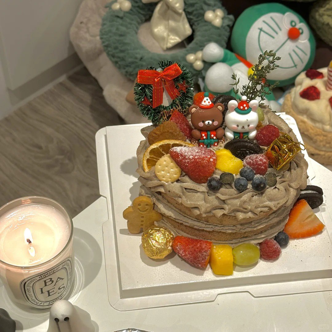 A festive holiday setup featuring a roasted chicken surrounded by colorful vegetables, a plate of pasta with seafood, and a glass of green beverage. A cake with adorable holiday decorations sits in the background, along with plush snowman decorations😋🥰