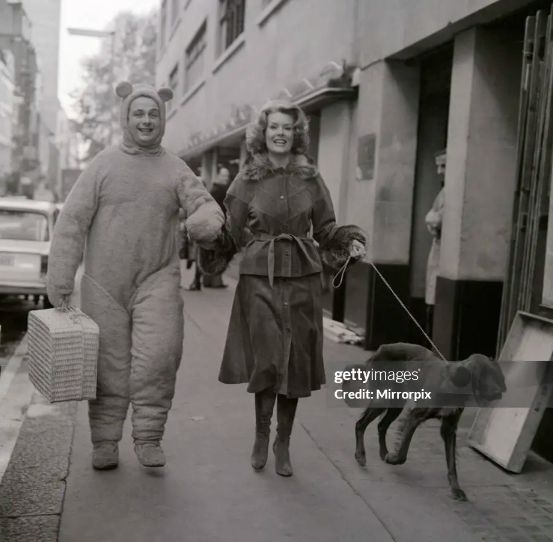 Nick_Metcalfe's tweet photo. I'm going to see Christopher Biggins in pantomime today. I've just had a look at pictures of Biggins in the Getty library and this isn't bad - here he is, with Sally Ann Howes, playing Winnie the Pooh in panto in London fifty years ago.

#Biggins #Panto https://t.co/P6EerjpgFd