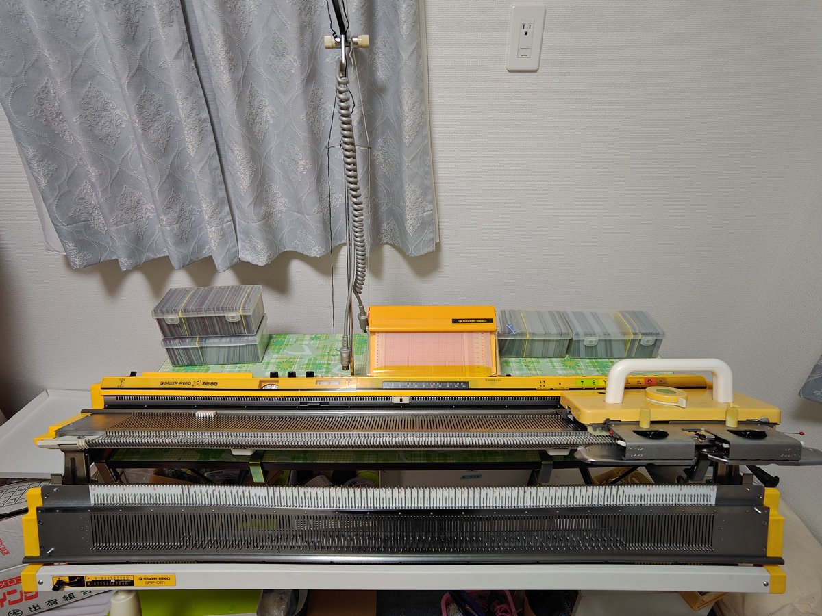 リブニッターで一目ゴム編み→オートウツシで本機に移動→創作カード読み込ませて編み込み できた！！
これでサイドをはいで上を絞ればきっとニット帽になるはず…
編み機が重くて前に倒れそうだったので昔集めてたカードを重しに(笑)
 #シルバー編み機  #編み物好きさんと繋がりたい  #ニット帽