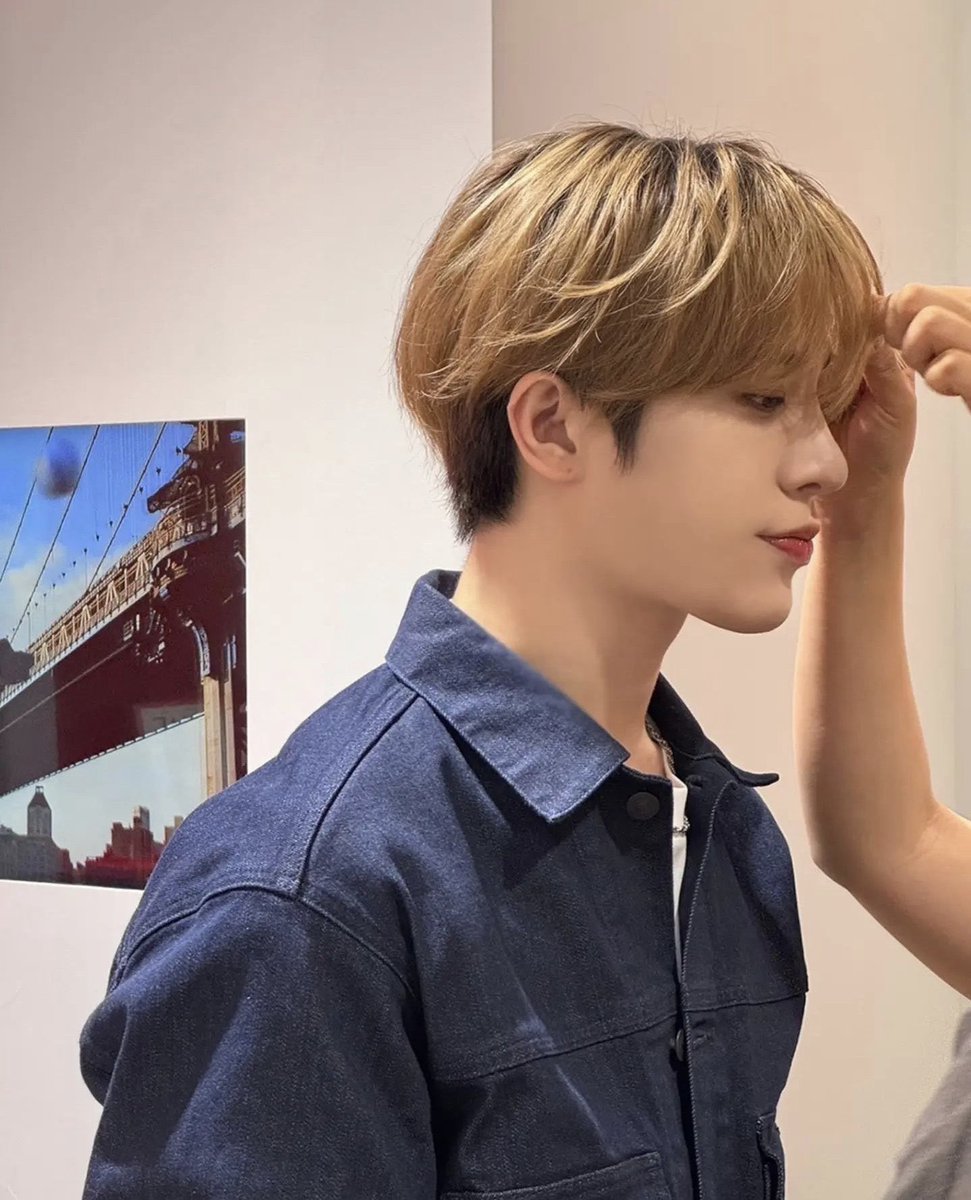 As gentle hands brush against the contours of our face, adjusting every strand with precise grace, we stand enveloped in the calm of creation. Here in this quiet alcove, against a backdrop of iconic bridges and bustling skylines, our reflection captures a softer introspection.