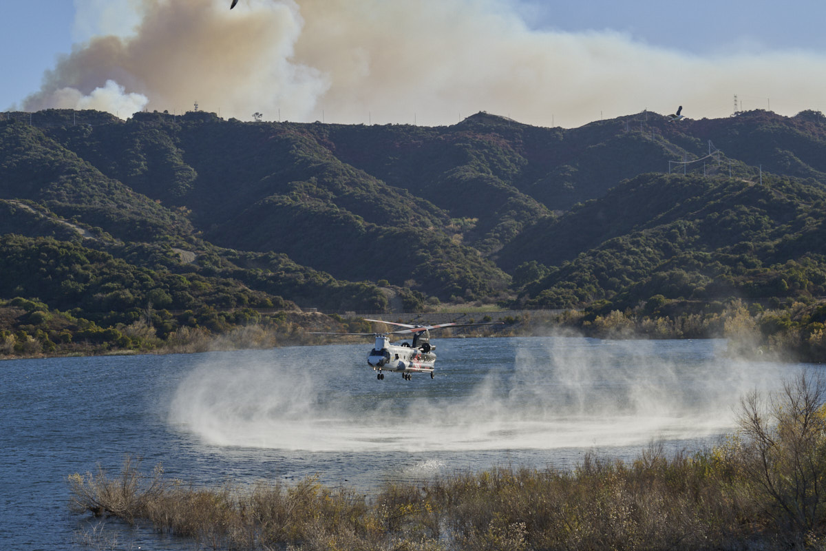 White helicopter touching down at a body of water.
