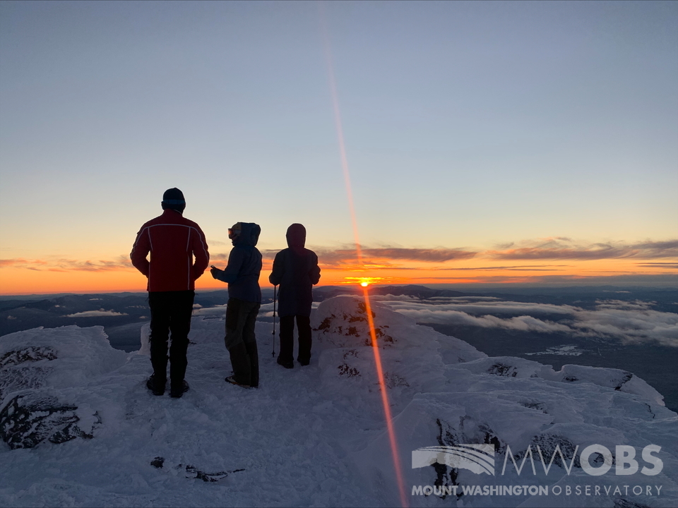 MWObs's tweet photo. After a busy full day of maintaining our summit weather station's operations, the crew treat themselves to a stunning Mount Washington sunset! Pictured are summit interns Mees and Marin, and summit volunteer Mei. #MWOBS #mountwashington #sunset #dusk #rockpile #abovetheclouds https://t.co/s9aThyPXaQ