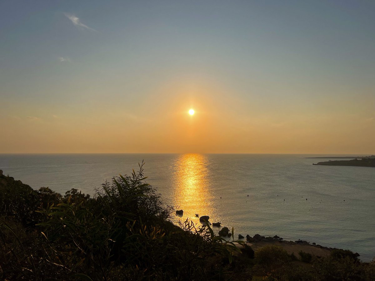 The golden light of the rising sun bathes the calm sea ...