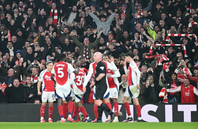 The Arsenal players and supporters celebrate together.
