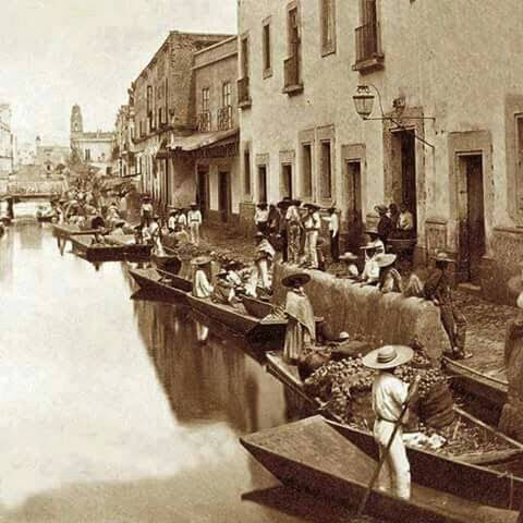 Impresionante postal del barrio de la Merced de alrededor de 1870 donde se aprecia la acequia de Roldán, la cual se adentraba en la ciudad de sur a norte. Al fondo se aprecia el Templo de la Santísima, así como varios puentes por los que transitaba la gente. Noten las piraguas, y