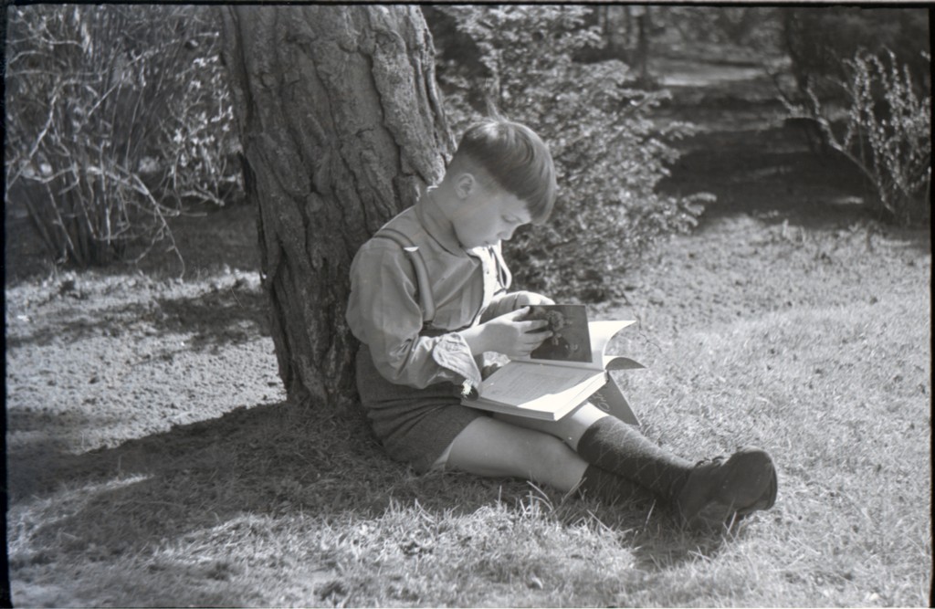 Een jongen zit tegen een boom in de zon geïnteresseerd een lesboek fotografie te lezen, 1950.

Bron: 0483-754-0226, C.R. Prins, CC-BY-4.0 licentie.