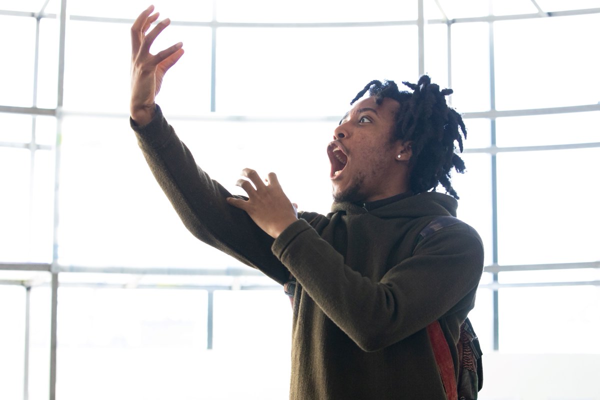 Pig Heart Boy in rehearsals. Photo by Ali Wright. A person wearing a brown top and with thick dark hair holds their hands up in front of them and scream.