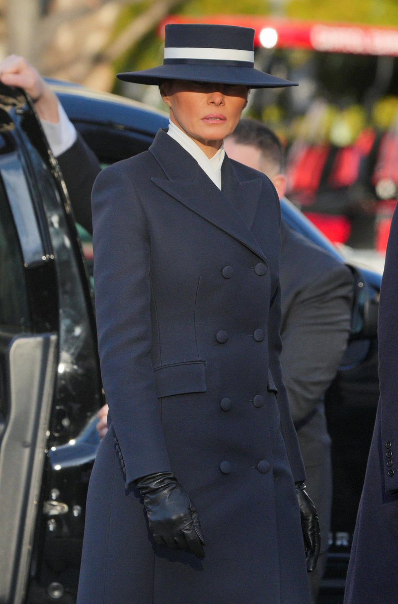 MELANIAJTRUMP's tweet photo. First Lady Melania Trump wore a custom double-breasted navy coat by Adam Lippes and a matching boater hat by Eric Javits, both American designers, for this morning’s church services as part of Inauguration ceremonies.

She completed this impeccable look with black leather gloves and dark blue suede Manolo Blahnik pumps. Melania’s look perfectly coordinated with her husband’s navy coat.
#FashionoftheFirstLady