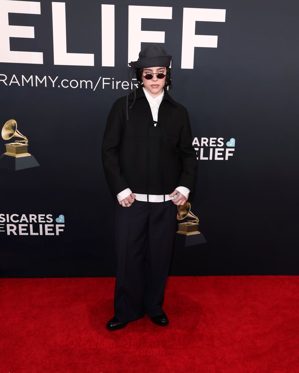 Billie Eilish wore a #Prada look inspired by Fall Winter 2016 collection  comprised of black jacket, white shirt, navy trousers, silver chain and black  lace-ups while attending the 67th Annual GRAMMY Awards. #