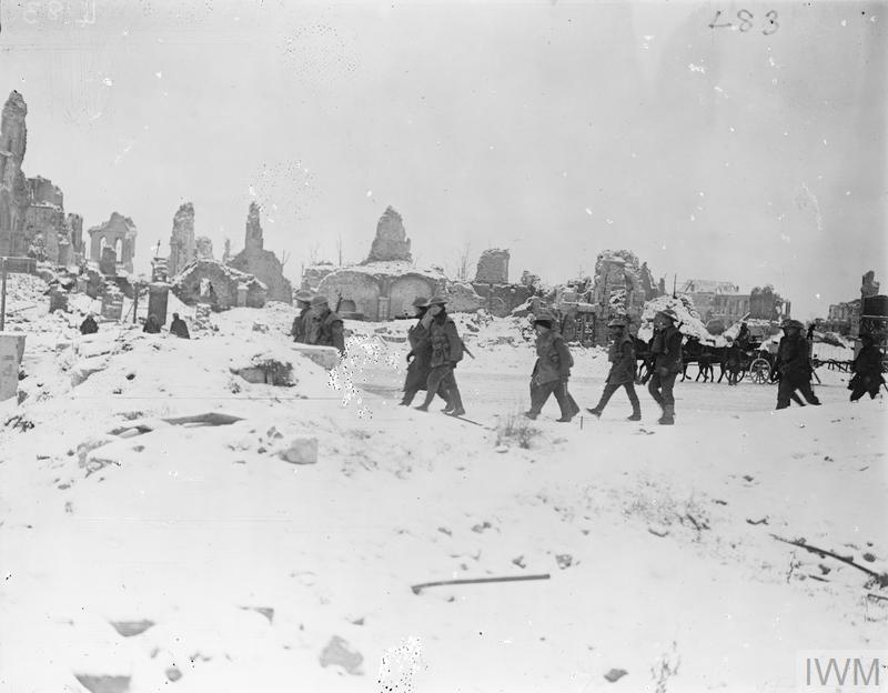 Troops on their way down from the line passing through the snow-covered ruins of Ypres, 8 January 1918.© IWM Q 8413