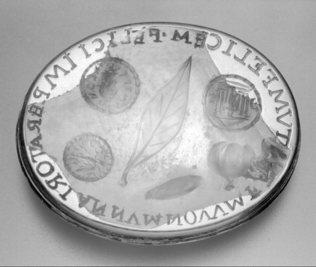 a gem expressing happy new year to #Commodus, accompanied by #Roman new year's gifts: a laurel leaf, a date, a fig and three #coins! The coins show a cult statue in a temple, Victory and the Commodus' portrait accompanied by this titles Pius and Felix. id.smb.museum/object/690778