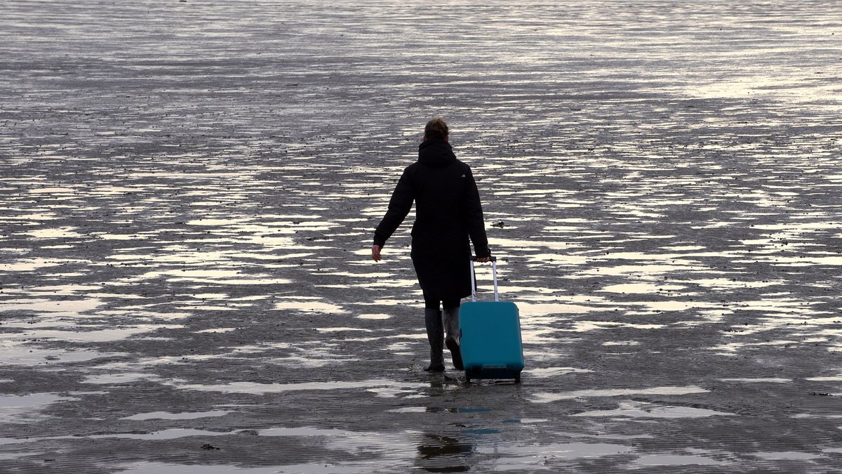 Shortcut van Maaike Meindertsma te zien tijdens LUNA Nights, 30 jan t/m 1 febr. Met een blauwe rolkoffer loopt een figuur door het slib van de Eems, de sneeuw in Duitsland en een droge vlakte in Tunesië naar een onbekende bestemming.