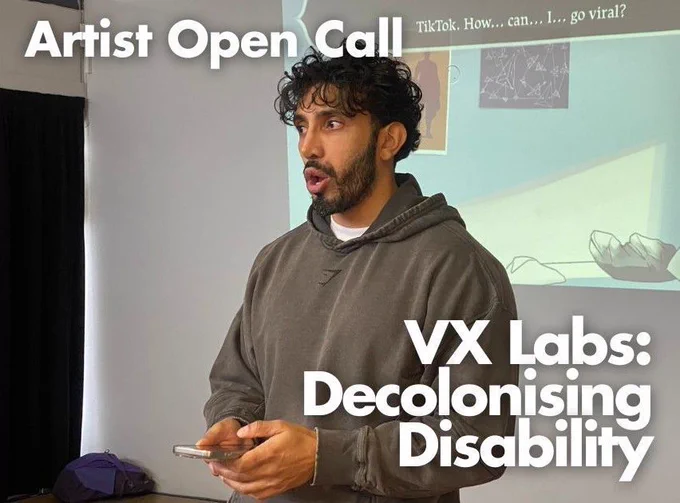 A man of South Asian heritage with a short beard, and dark floppy hair. He holds an iPhone, texting, and looks out in front of him. His mouth is open, talking and his expression is serious. In the background an cartoon drawing of a bedroom is projected, with the caption 'TikTok. How...can..I..go viral?' Text overlayed on the whole image reads 'Artist Open Call. VX Labs: Decolonising Disability'
