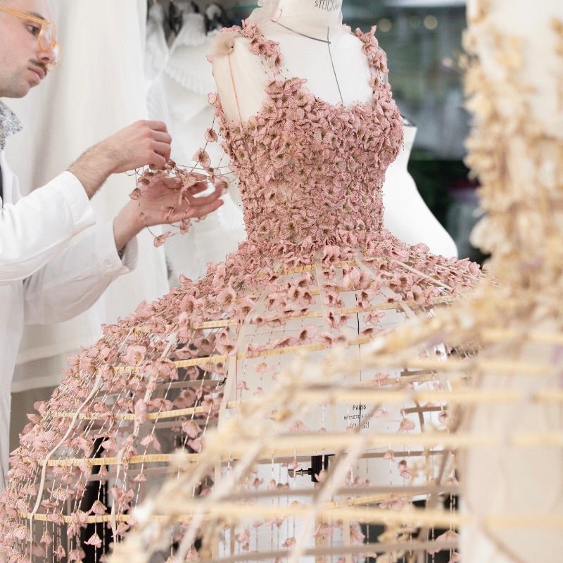 Dior's tweet photo. Evoking 'Alice in Wonderland', a medley of #DiorCouture Spring-Summer 2025 crinoline gowns by Maria Grazia Chiuri each sprouted up to 1400 softly hued fabric flowers, handcrafted by the Chanakya atelier artisans in a poetic expression of #DiorSavoirFaire.