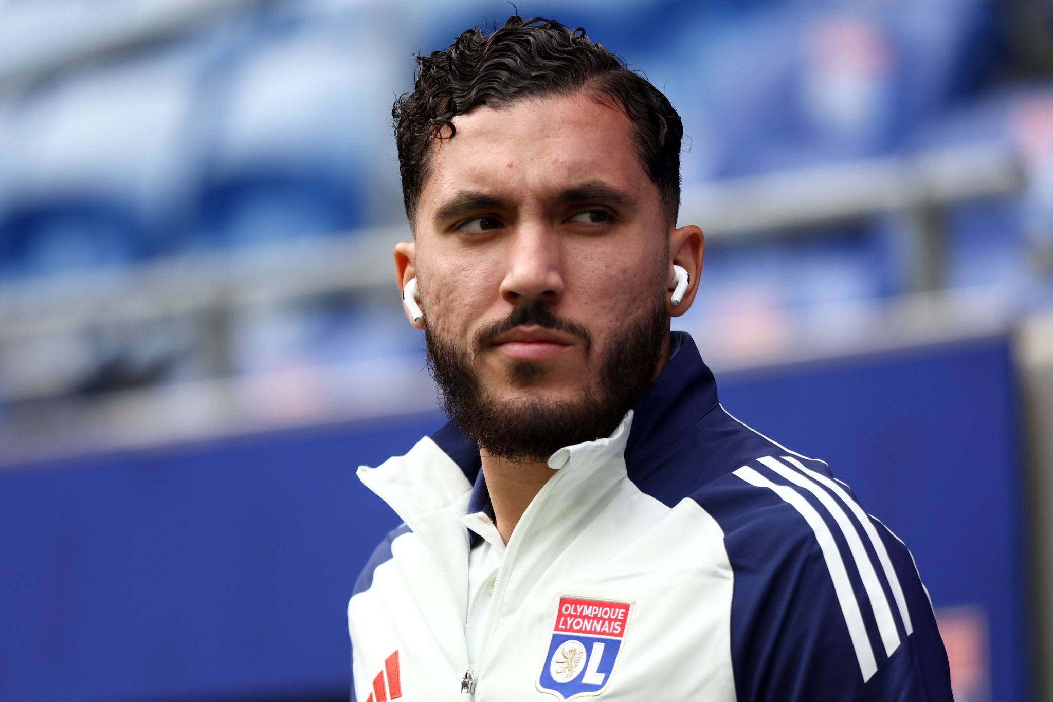 Rayan Cherki mira a su hombro izquierdo en un chándal de Lyon.