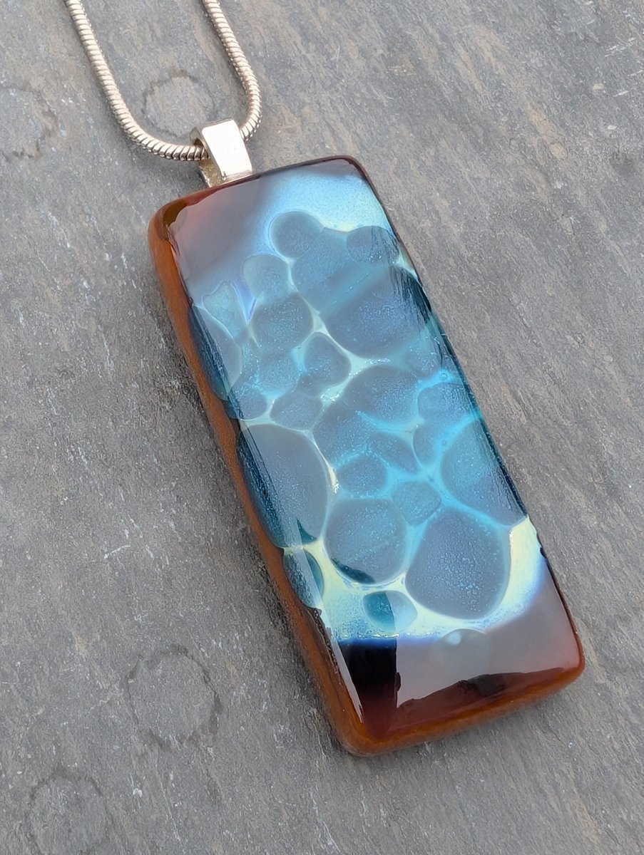 Stunning new handcrafted reactive glass necklace. Beautiful pools of blue within this bronze, blue and silver leaf pendant. Unique pendant. 

#ukgiftidea #ukgiftam #handmade #etsy #shopindie #giftideas

buff.ly/3QhDAKn