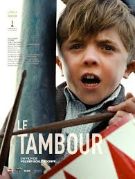merlinpapin3's tweet photo. .@FredOL69007 #DéfiCinéClassique2025 Février (Anatole Dauman) avec le film #LeTambour de  Volker Schlöndorff(1979) avec David Bennent Mario Adorf Angela Winkler Charles Aznavour Tina Engel Katharina Thalbach Berta Drews Daniel Olbrychski

L'histoire du Tambour est racontée sous la forme d'un long monologue, dont le narrateur n'est autre que le héros lui-même, Oskar Matzerath, un bien étrange personnage qui a incroyablement survécu, avec sa grand-mère protectrice, à la Seconde guerre mondiale. Doté d'une intelligence hors du commun, il reçoit en cadeau, pour son troisième anniversaire, le 12 septembre 1927, un tambour de fer-blanc laqué rouge et blanc. Choqué par le monde des adultes, il décide de cesser de grandir. Pour cela, il fait exprès de tomber du haut des escaliers de la cave de sa maison et va ainsi conserver sur le monde un regard d'enfant implacable et inflexible. Il découvre qu'il a le talent particulier de pousser un cri strident de haute fréquence qui casse le verre alentour.

Volker Schlöndorff signe avec Le Tambour (Die Blechtrommel), adapté du roman éponyme de Günter Grass, une œuvre fascinante et dérangeante, où l’enfance se mue en résistance face à un monde en décomposition. Coécrit avec Jean-Claude Carrière, le scénario suit le parcours d’Oskar Matzerath, un enfant qui, par un acte de refus absolu, décide à trois ans de ne plus grandir après une chute sur la tête. Son instrument fétiche, un petit tambour rouge et blanc, devient son unique langage, une arme contre la médiocrité et la brutalité des adultes.

David Bennent, âgé de 11 ans au moment du tournage, livre une performance inoubliable, incarnant ce personnage à la fois enfantin et inquiétant. Son regard perçant, sa maturité troublante et son cri strident – capable de briser le verre – donnent à Oskar une dimension quasi mythologique. Il traverse l’histoire de l’Allemagne des années 1920 aux lendemains de la Seconde Guerre mondiale avec une lucidité qui le distingue de son entourage aveuglé par l’idéologie.

Le film ne recule devant rien pour illustrer la montée du nazisme et la compromission générale. La scène où Oskar interrompt un rassemblement hitlérien en détournant une marche militaire vers une valse grotesque est l’un des moments les plus marquants du film : son tambour devient une force subversive, un instrument de révolte contre l’ordre établi. Mais cette rébellion ne suffit pas à arrêter la marche inexorable du chaos.

Un des aspects les plus controversés du film reste la relation entre Oskar et Maria, une jeune femme plus âgée. Cette scène, jugée choquante par certains, interroge les frontières de l’enfance et de la sexualité dans un corps resté figé à trois ans. Oskar, malgré son apparence, est un être hybride, un esprit adolescent dans un corps d’enfant, ce qui rend ces moments profondément troublants.

Visuellement, Schlöndorff restitue avec brio l’atmosphère du Dantzig d’avant-guerre, ville cosmopolite où se croisent Allemands, Polonais et Cachoubes. L’omniprésence du tambour d’Oskar rythme le film comme une litanie funèbre, battant la mesure d’un monde qui court à sa perte.

La Palme d’Or obtenue en 1979, partagée avec Apocalypse Now, souligne la puissance du film : deux visions de la guerre, l’une hallucinée et infernale chez Coppola, l’autre cruelle et grotesque chez Schlöndorff. L’Oscar du Meilleur Film Étranger en 1980 viendra consacrer ce chef-d’œuvre du cinéma allemand.

David Bennent, après ce rôle emblématique, n’a jamais connu une carrière aussi marquante, bien qu’il ait continué à tourner au cinéma et au théâtre. Mais son visage, figé dans le temps, hante toujours ceux qui ont croisé son regard sur grand écran. Le Tambour reste une fable tragique sur l’impossible innocence et la déliquescence d’une époque, un film dont on ne sort pas indemne.