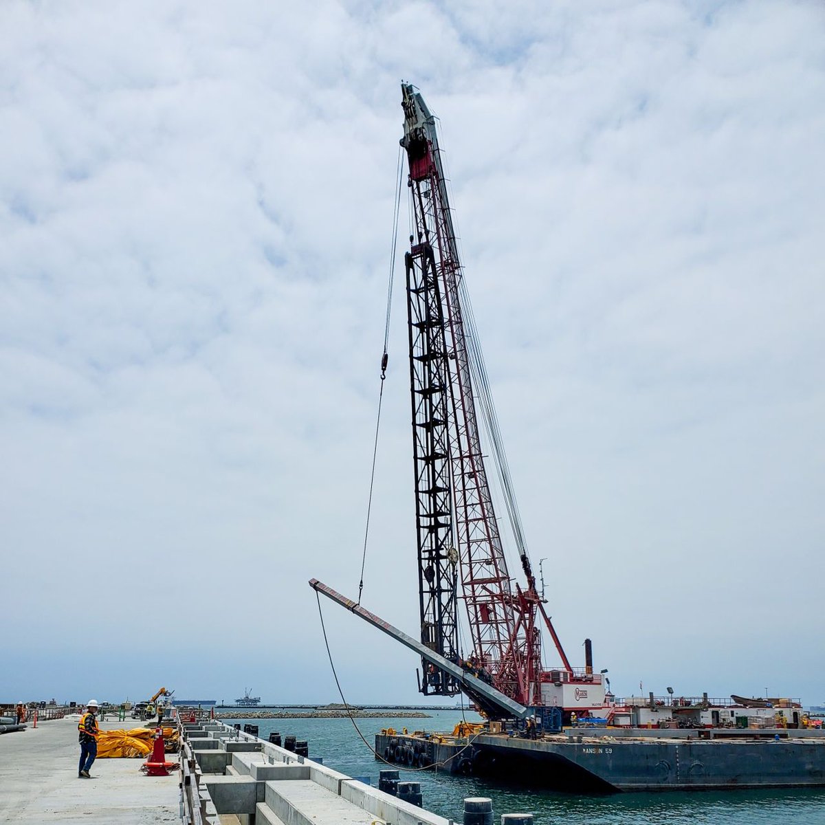 Manson's derrick barge VALKYRIE lofting the first concrete fender pile for driving.  Foremen Jeff Jensen and the VALKYRIE crew recently drove the concrete-filled fiberglass reinforced plastic piles.
Credit: Manson Construction Co.
#Pilebuck #marineconstruction #dredging