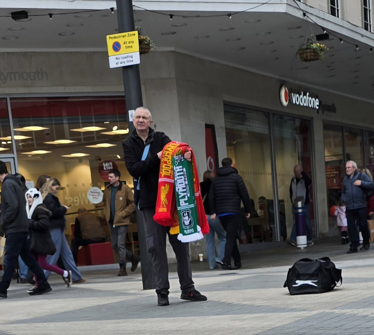 AnFlanders's tweet photo. Scenes of heartbreak and devastation across Plymouth City Centre today ahead of Argyle v Liverpool in the FA Cup tomorrow.  Not many takers for the half and half scarves and the 🇳🇬 Argyle🇳🇬 badge is so stretched - dreadful craftsmanship. #ARGLIV #PLYLIV
#PAFC https://t.co/HsEMwDjGaG