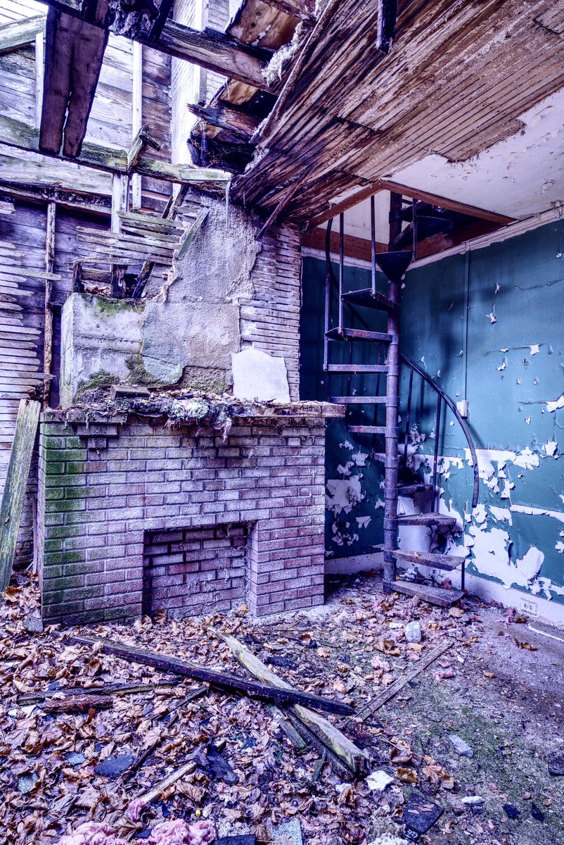 Spiral staircase in the living room of an abandoned house. The remnants of a unique remodel of an early 1900s house.