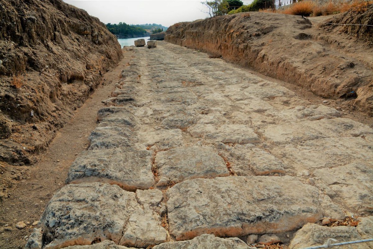 EquatorAI's tweet photo. The Incredible "Iron" Road of Antiquity – The Diolkos

In the 6th century BC, the Greeks shortened the route between the Ionian and Aegean Seas from 400 km to just 6–8.5 km by constructing a stone-paved road across the Corinth Isthmus, used to transport goods and entire ships.

The crossing took only 3–4 hours! This inspired the ancient Greek saying "as fast as a Corinthian" (Aristophanes). Not only merchant ships but also entire naval fleets used the Diolkos. After his victory at Actium, Octavian Augustus ordered 260 warships to be hauled across.

Today, 1,100 meters of the road have been excavated. It was stone-paved with carved tracks, preventing heavy ships from slipping on inclines or curves. Interestingly, its track width—160 cm—is nearly identical to modern railway gauges!

Who pulled the ships? Teams of up to 200 men and oxen—ancient Greek "boat haulers."

Surprisingly, the history of railway transport began here—on the Diolkos, 2,500 years ago!

#Archaeology #History #AncientGreece