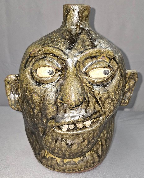 AntiqueDigest's tweet photo. Lanier Meaders (1917-1998) rock-tooth face jug sold for $2880 (e. $1700/3000) at Cagle Auction. It is 10" tall, with 4 rock teeth and a sidewise glaring look highlighted with bold ash glaze runs https://t.co/6ldlQYgb1O #antiques #antique #folkart #facejug #stoneware #Meaders https://t.co/hKmvbAB3cc