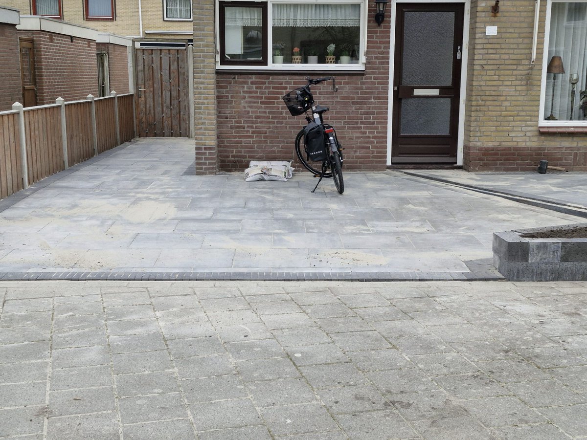 🌱 Bij deze klant mochten wij nieuwe bestrating aan de voorkant van de woning aanbrengen. De klant wilde dat er een terras gerealiseerd werd waar ze met mooi weer van kunnen genieten. Door het terras 30° te draaien en iets minder af te laten lopen, geeft dit een speels effect.