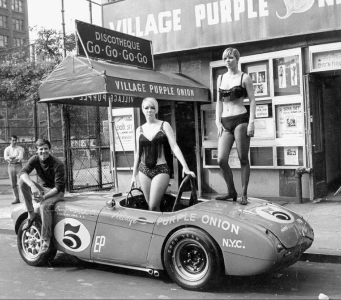 An Austin Healey “Big Healey” sports car, &amp; some go-go dancers, outside the Purple Onion Discotheque on West 3rd St. in Greenwich Village NYC in 1968. Sitting on the front hood is race car driver Jerry Walsh whose car is purple, was sponsored by the club.

amzn.to/42RvqzD