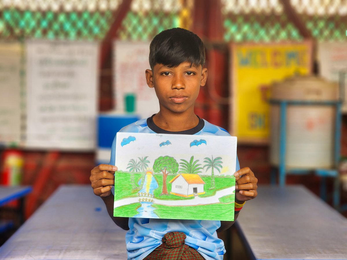 youthfularfat's tweet image. A talented Rohingya student proudly showcases his latest artwork, a vibrant scene of a peaceful village, complete with a small house, a winding stream, and tall palm trees swaying gently under a clear sky.
#Rohingya #talentchallenge 
#refugeechildren #camplife