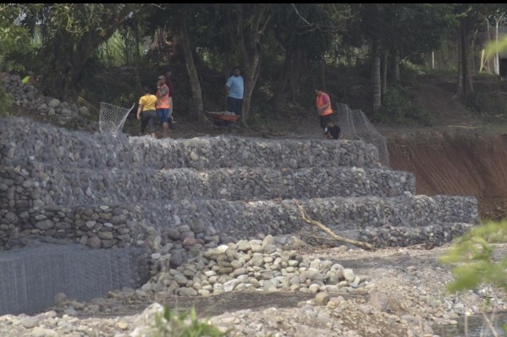 luislemushn's tweet photo. Sentada en una piedra que luego cargará, Suyapa Ríos, aprovecha la sombra de un árbol; mientras agarra aire, para retomar su tarea de armar gaviones. Esta mujer es la que ha levantado esta barrera en el río Bonito, para protejer a colonias de El Porvenir, en Atlántida. https://t.co/jRm389g8eQ