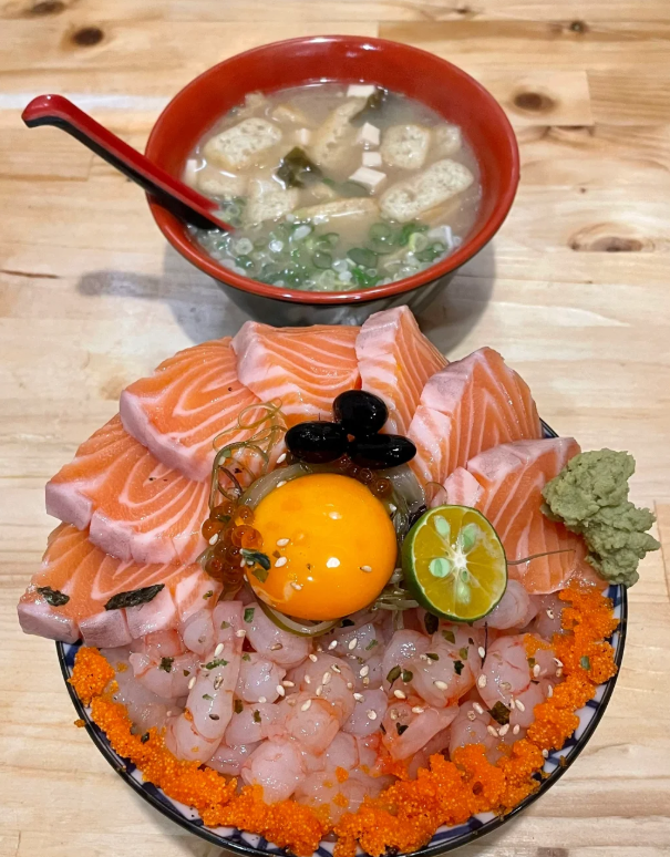 サーモンと甘エビの丼は食欲をそそる日本料理です！ 🌊🍣 新鮮なサーモンのスライスと甘エビの完璧な組み合わせに、香り高く柔らかい白米が加わり、味わい深く、本当に美味しいです！ 🥢✨ 醤油とマスタードを少しかけるとさらに風味が増し、一口ごとに驚きがいっぱいになります! 🤤🍚