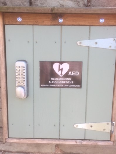 The village defibrillator is on a wall in the Moody Cow car park. In an emergency ring 999 and you will be given the code to access it.
