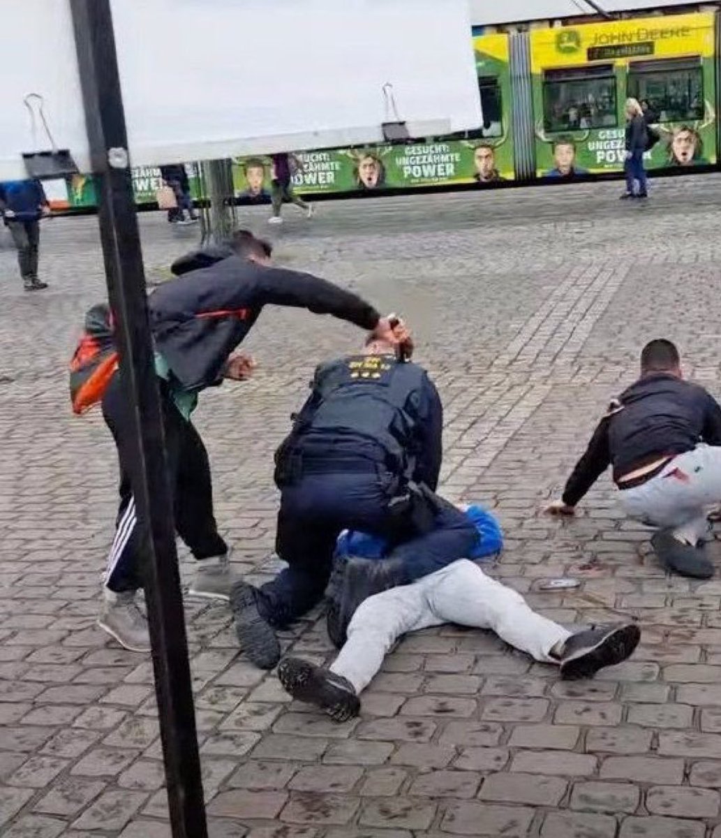 visegrad24's tweet image. This photo from 2024 is perhaps the perfect visual representation of Germany:

A police officer subduing the victim of an Islamist attack while the Islamist, who had been detained by patriotic citizens, broke free and stabbed the police officer in the back, killing him.