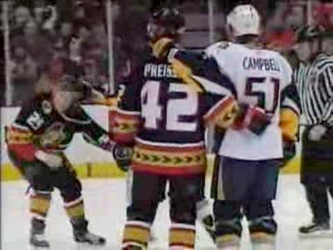 two hockey players holding each other and watching a fight unfold in front of them