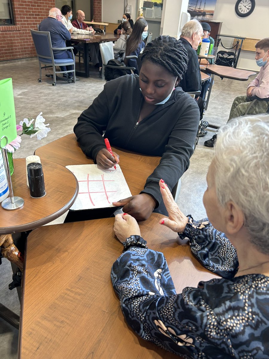YFAs having fun playing cards with their Grand Friends